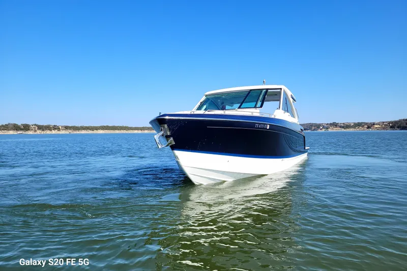 Slide: The Image of 2023 Formula 380 Super Sport Crossover I/O on a serene lake under clear blue skies. - 4