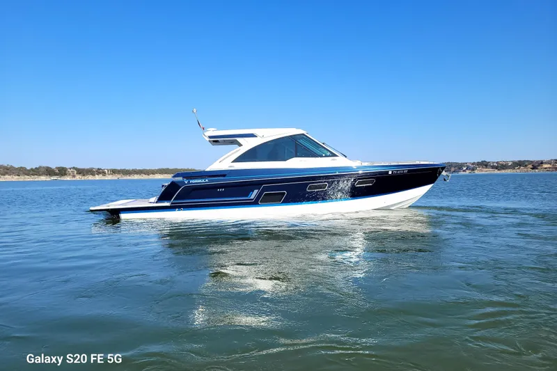 Slide: The Image of 2023 Formula 380 Super Sport Crossover I/O boat cruising on a calm lake. - 8