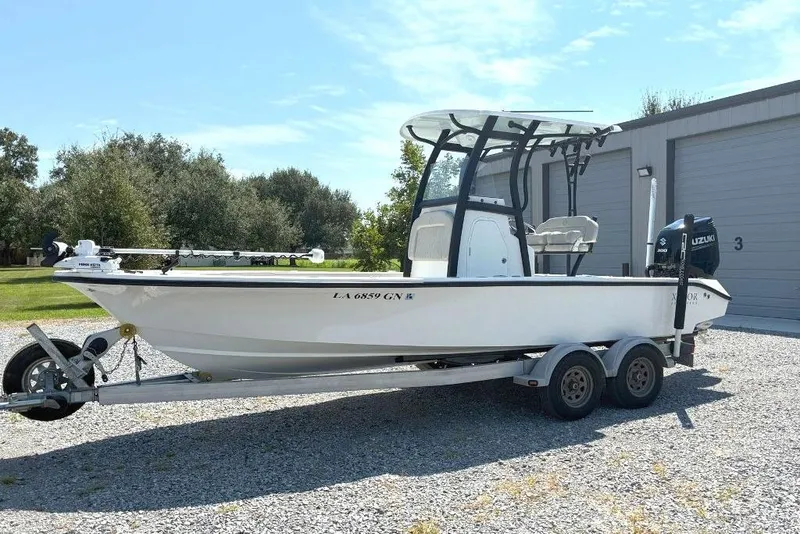 Slide: The Image of 2023 Xplor X24 boat on trailer, parked outdoors near a garage. - 2