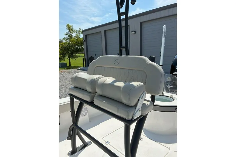 Slide: The Image of 2023 Xplor X24 boat seat with cushioned backrest and armrests, outdoors near a garage. - 23