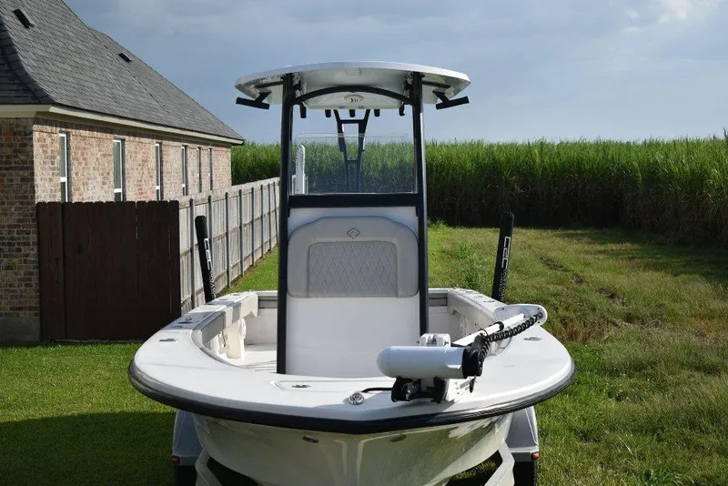 Slide: The Image of 2023 Xplor X24 boat parked on grass near a brick house and tall grass. - 7