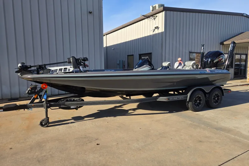 The Image of 2026 Skeeter ZXE21 fishing boat on trailer, parked outside a metal building. - 11