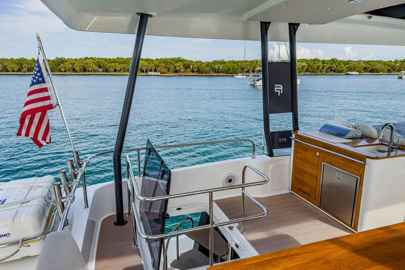 Slide: The Image of 2022 Fountaine Pajot MY6 yacht deck with American flag, outdoor kitchen, and ocean view. - 7