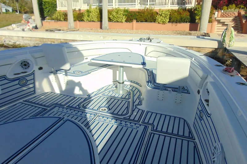 Slide: The Image of 2019 Stamas 390 Tarpon boat interior with seating and table, docked near a garden. - 8