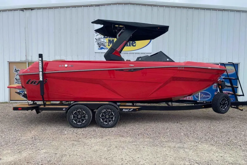 The Image of 2026 Tigé Z3 boat in vibrant red on a trailer, parked outside a marine shop. - 0