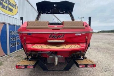 Slide: The Image of 2026 Tigé Z3 boat, red exterior, parked near a marine supply store. - 4