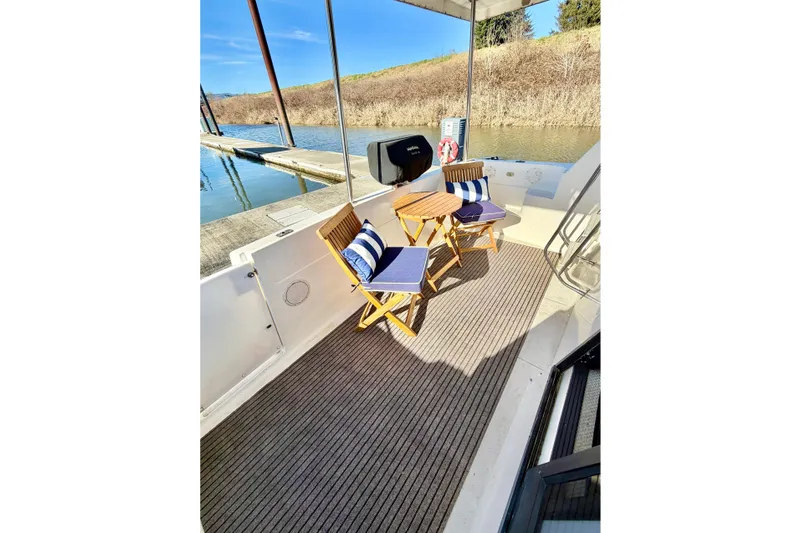 Slide: The Image of 2002 Bayliner 3988 Command Bridge Motoryacht deck with chairs and table by the water. - 15