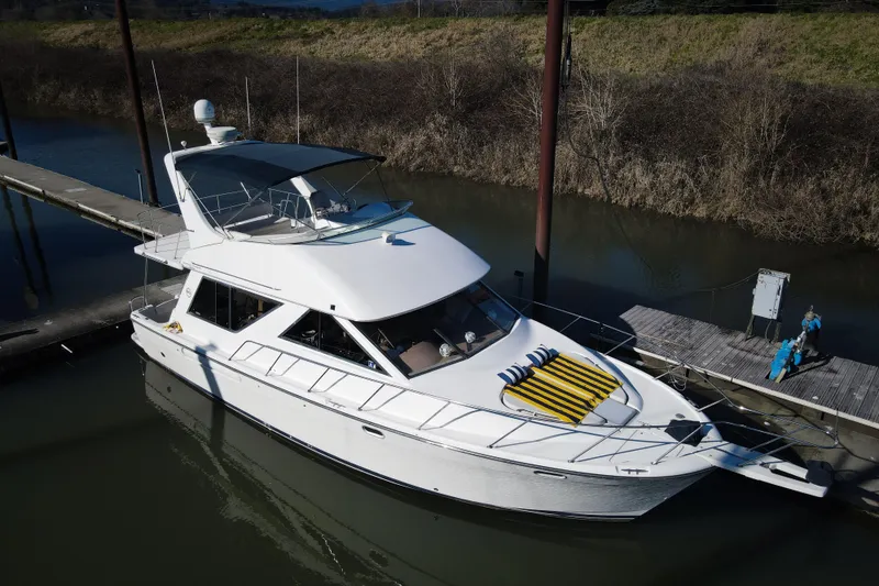 Slide: The Image of 2002 Bayliner 3988 Command Bridge Motoryacht docked in a serene marina setting. - 3
