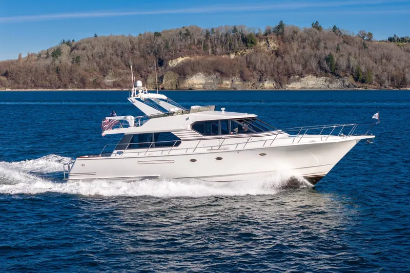 Slide: The Image of 1998 West Bay 58 Sonship Pilothouse MY cruising on blue water near a forested shoreline. - 4