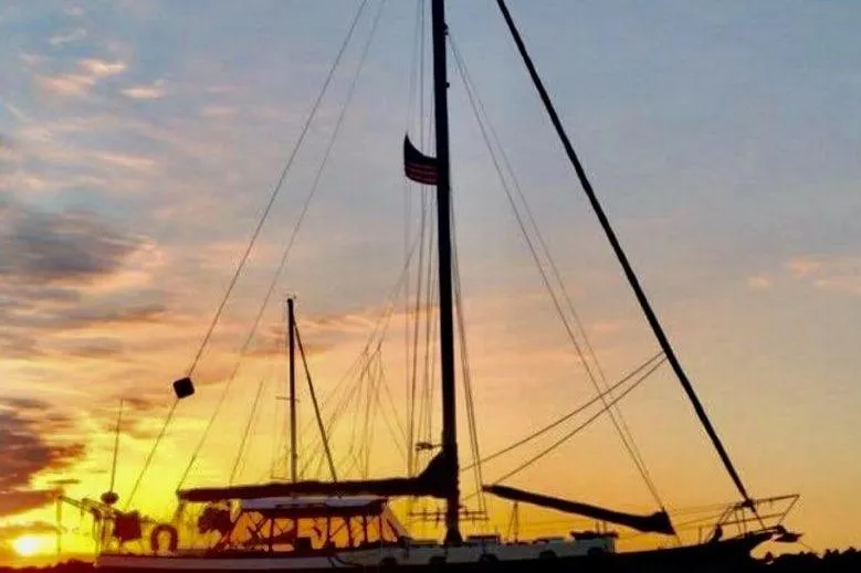 Slide: The Image of 1979 CSY 44 CC sailboat silhouetted against a vibrant sunset sky. - 55