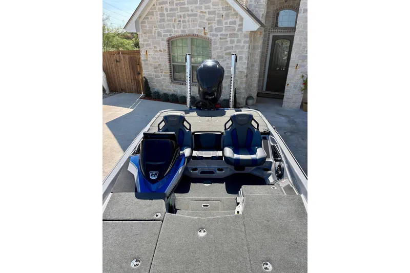 Slide: The Image of 2021 Skeeter FXR21 boat with dual seats, parked in front of a stone house. - 6