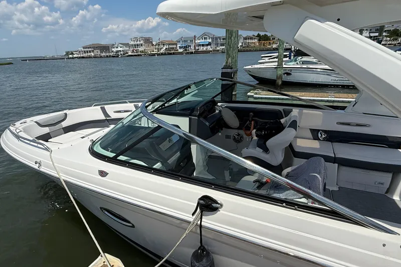 Slide: The Image of 2019 Chaparral 297 SSX boat docked by waterfront homes under a clear sky. - 10