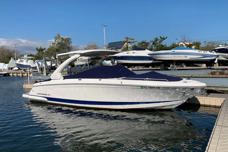 Slide: The Image of 2019 Chaparral 297 SSX boat interior with white seating and deck at a marina. - 12