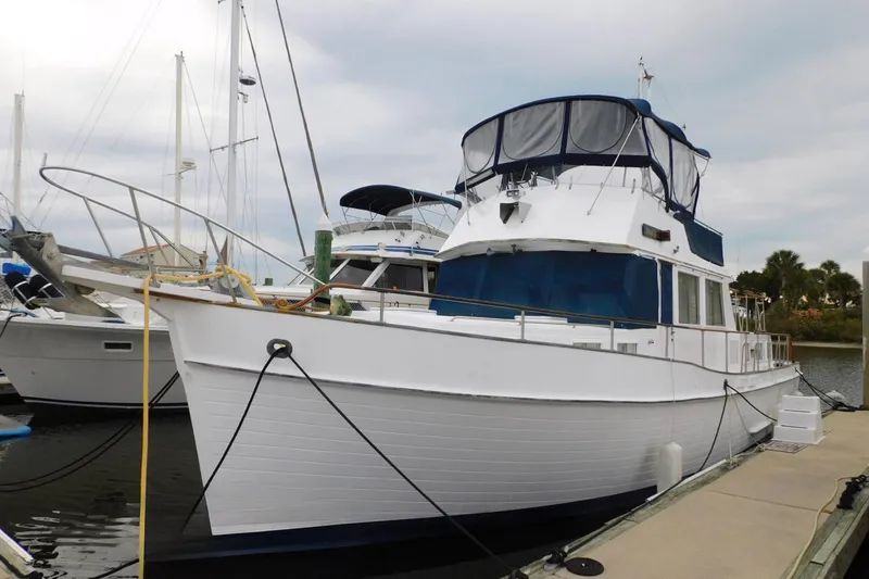 Slide: The Image of 1986 Grand Banks 46 Classic yacht docked at marina, featuring blue canopy and white hull. - 2