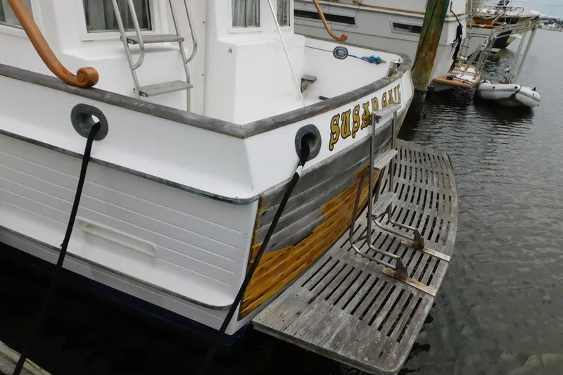 Slide: The Image of 1986 Grand Banks 46 Classic boat docked, featuring wooden swim platform and ladder. - 23