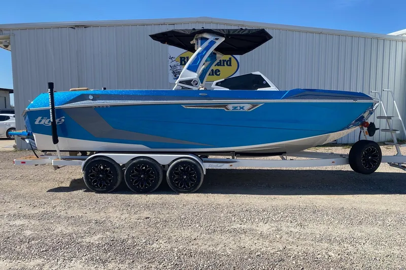The Image of 2025 Tigé Ultré 25ZX boat in vibrant blue on a trailer, parked outdoors. - 1