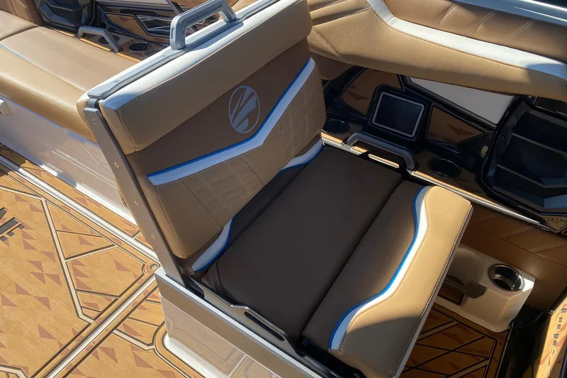 Slide: The Image of 2025 Tigé Ultré 25ZX boat interior with tan and blue seating, cup holders, and patterned flooring. - 10