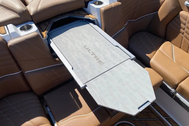 Slide: The Image of 2025 Tigé Ultré 25ZX boat interior with brown leather seats and foldable table. - 14
