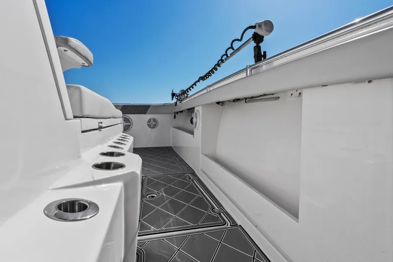 Slide: The Image of 2024 Invincible 46 Catamaran deck with rod holders and seating, under clear blue sky. - 11