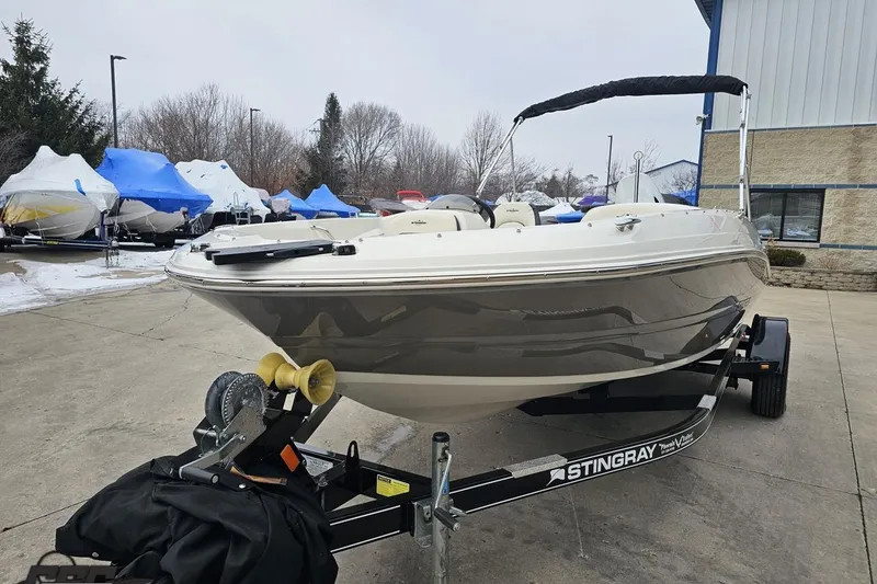 Slide: The Image of 2022 Stingray 182 SC boat on trailer, parked outdoors near covered boats. - 15