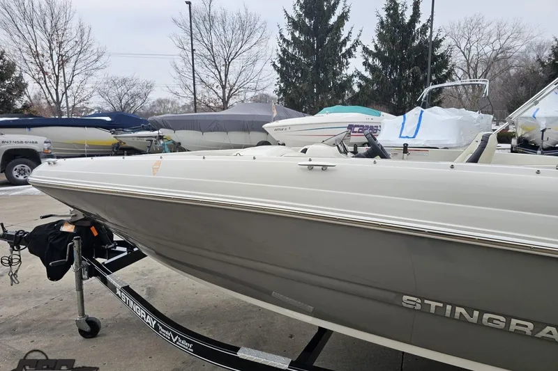 Slide: The Image of 2022 Stingray 182 SC boat on trailer, parked outdoors with other boats. - 21
