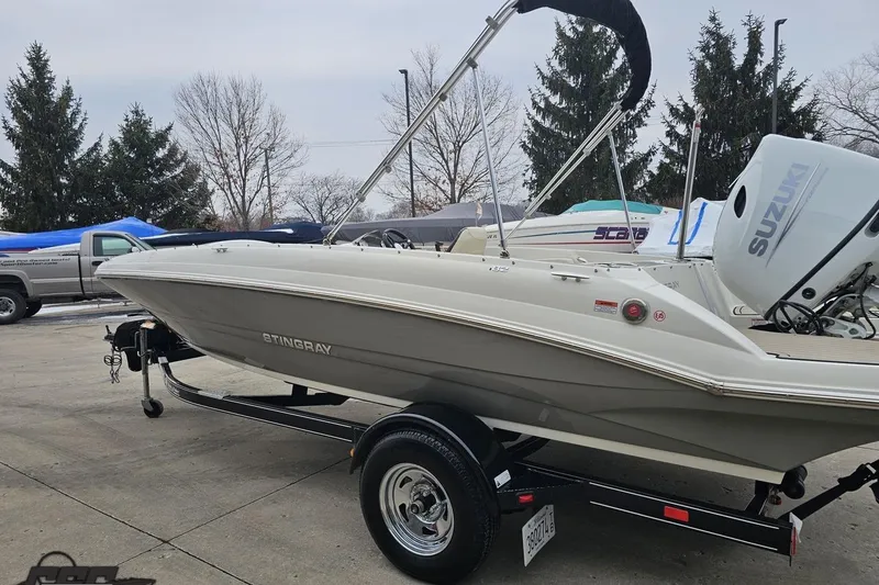 Slide: The Image of 2022 Stingray 182 SC boat on trailer with Suzuki outboard motor, parked outdoors. - 23