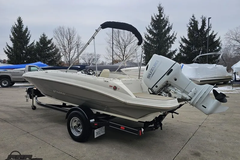 Slide: The Image of 2022 Stingray 182 SC boat with Suzuki outboard motor on trailer, parked outdoors. - 24