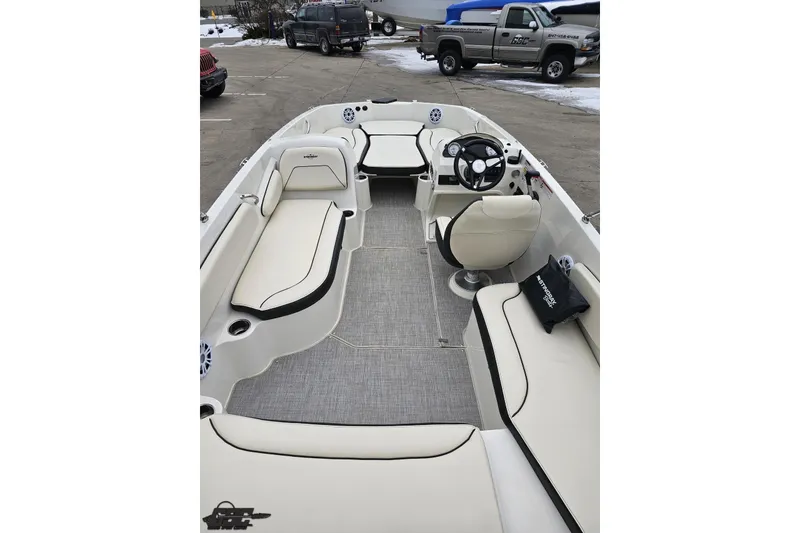 Slide: The Image of 2022 Stingray 182 SC boat interior with seating and steering wheel, parked outdoors. - 34