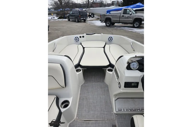 Slide: The Image of 2022 Stingray 182 SC boat interior with seating and dashboard, parked outdoors. - 59