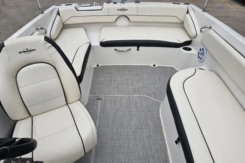 Slide: The Image of 2022 Stingray 182 SC boat interior with white cushioned seating and gray flooring. - 75