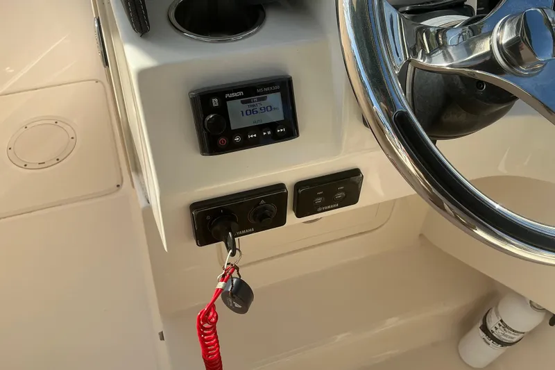 Slide: The Image of 2020 Grady-White Freedom 275 boat dashboard with steering wheel and radio controls. - 19