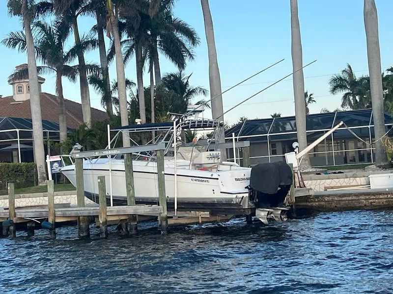 Slide: The Image of 2001 Contender 35 Side Console boat docked by palm trees and waterfront homes. - 10