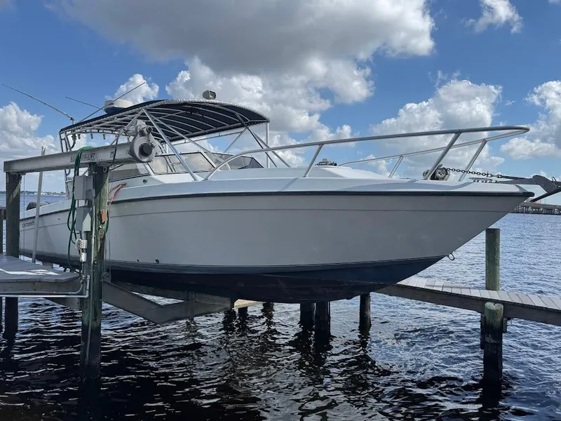 Slide: The Image of 2001 Contender 35 Side Console boat docked by the water under a cloudy sky. - 2
