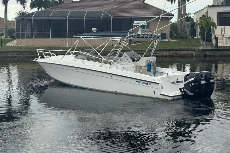 Slide: The Image of 2001 Contender 35 Side Console boat with dual Mercury engines on a calm waterway. - 32