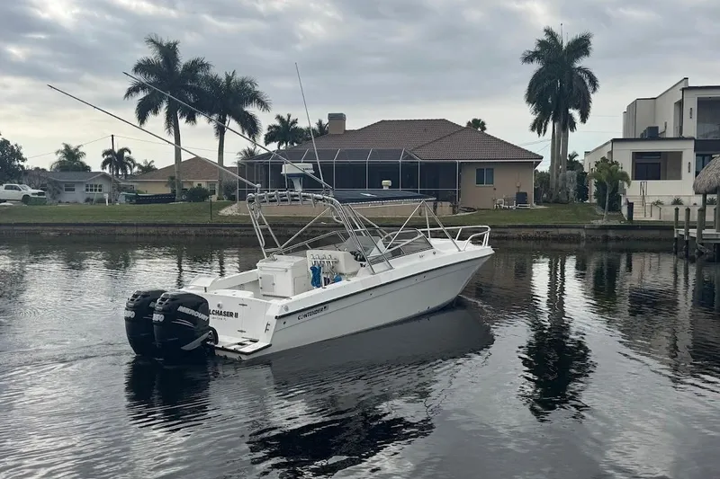 Slide: The Image of 2001 Contender 35 Side Console boat on a calm canal with palm trees and houses. - 33