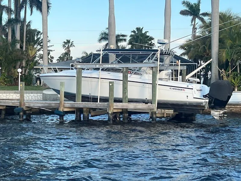 Slide: The Image of 2001 Contender 35 Side Console boat docked by palm trees, with calm water in the foreground. - 8