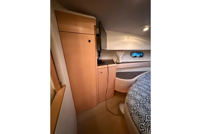 Slide: The Image of 1998 Bayliner 3685 Avanti Sunbridge cabin interior with bed, cabinet, and porthole window. - 3