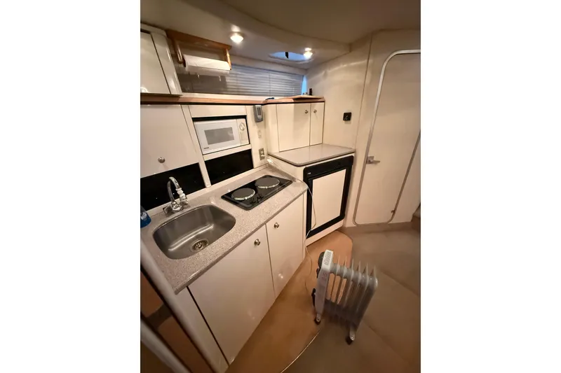 Slide: The Image of 1998 Bayliner 3685 Avanti Sunbridge interior kitchen with sink, stove, and microwave. - 7