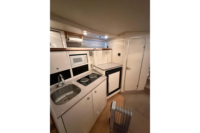 Slide: The Image of 1998 Bayliner 3685 Avanti Sunbridge interior kitchen with sink, stove, and microwave. - 8