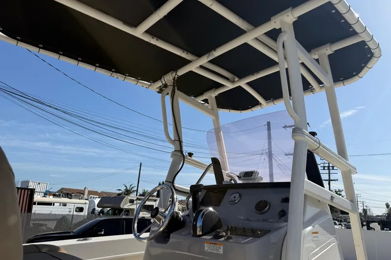 Slide: The Image of 2022 2 Bar T22 CX boat console with steering wheel and canopy under clear sky. - 7