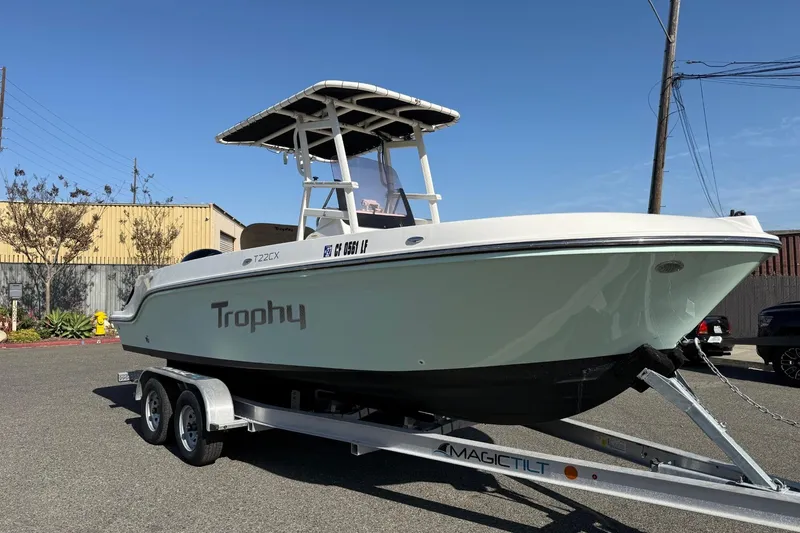 Slide: The Image of 2022 2 Bar T22 CX boat on trailer, labeled "Trophy," under clear blue sky. - 11