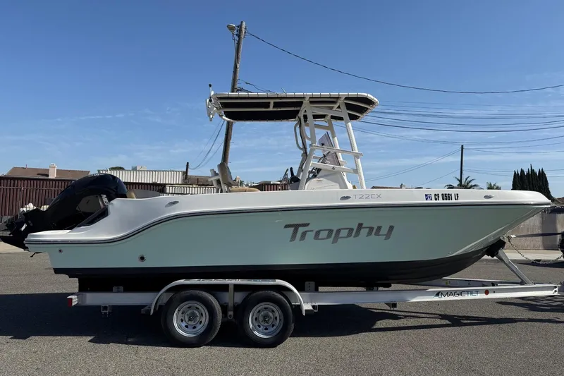 Slide: The Image of 2022 2 Bar T22 CX Trophy boat on trailer, parked outdoors under clear sky. - 12