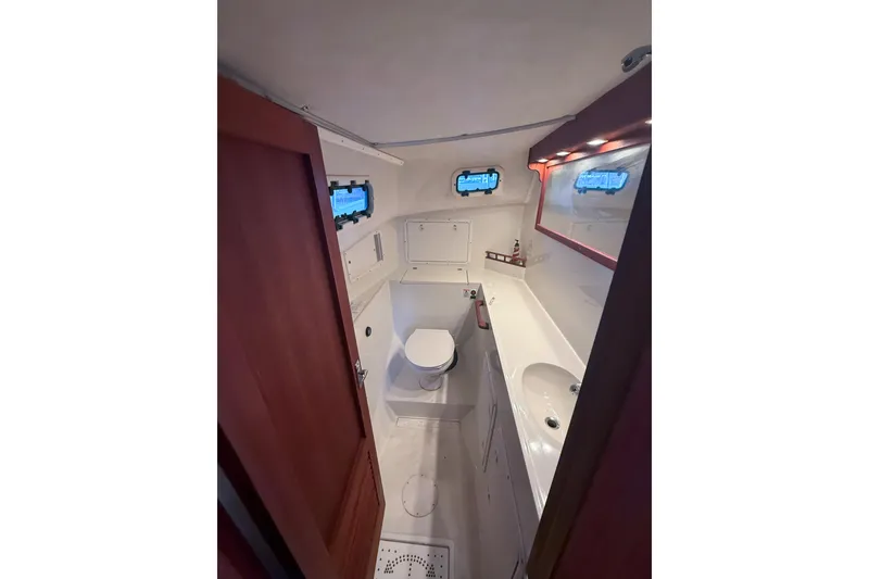 Slide: The Image of 2003 SeaSport Pacific 3200 boat bathroom with toilet, sink, and porthole windows. - 19