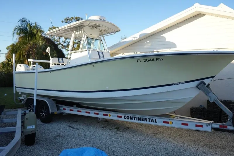 The Image of 1999 Regulator 26 Forward Seating boat on trailer, parked beside a house. - 0