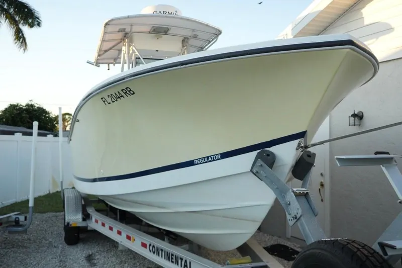 Slide: The Image of 1999 Regulator 26 Forward Seating boat on trailer, parked outdoors. - 23