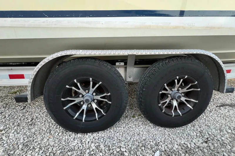 Slide: The Image of Trailer wheels of a 1999 Regulator 26 Forward Seating boat on gravel. - 24