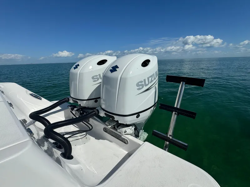 Slide: The Image of 2022 Aquasport 2500 Center Console with twin Suzuki outboard motors on open water. - 11