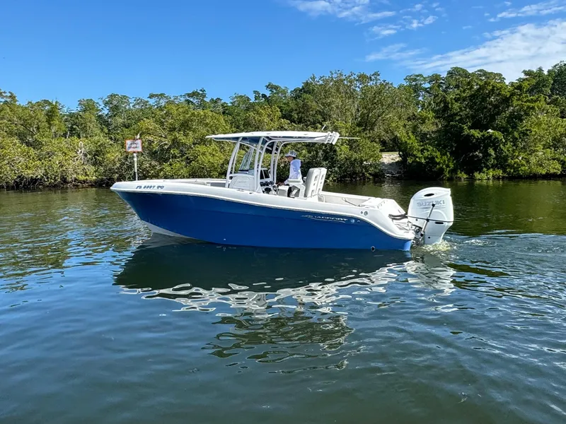 Slide: The Image of 2022 Aquasport 2500 Center Console boat on calm water with lush greenery in the background. - 2