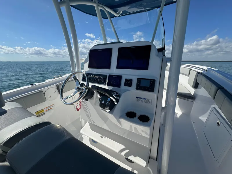 Slide: The Image of 2022 Aquasport 2500 Center Console boat dashboard with dual screens on open water. - 21