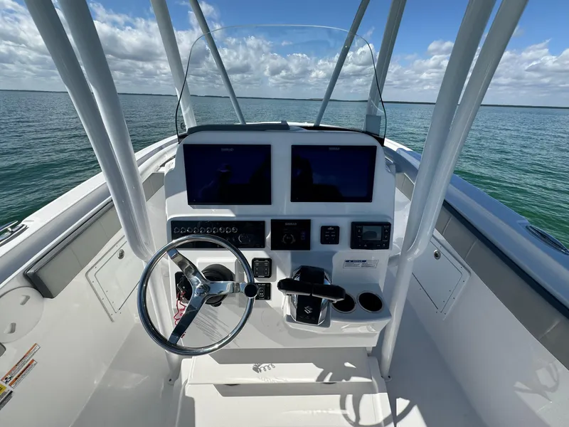 Slide: The Image of 2022 Aquasport 2500 Center Console boat dashboard with dual screens on open water. - 22
